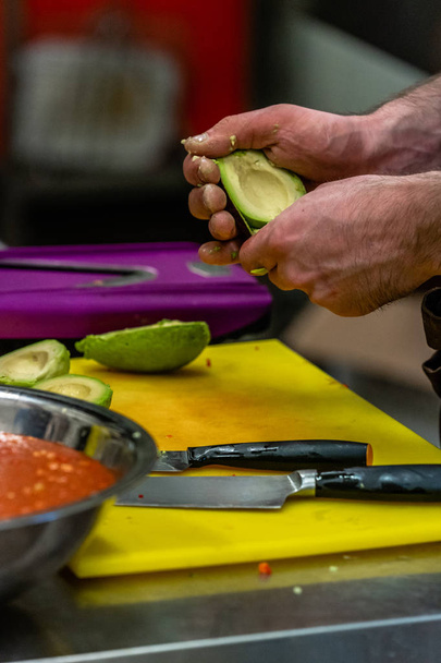 Chef masculino Pealing Aguacate para la comida de boda - Cocina con acción aislada, solo manos del chef
 - Foto, imagen