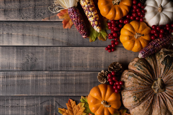 Bovenaanzicht van Autumn maple laat met pompoen, appel, maïs en rode bessen op oude houten achtergrond. Thanksgiving day concept. - Foto, afbeelding