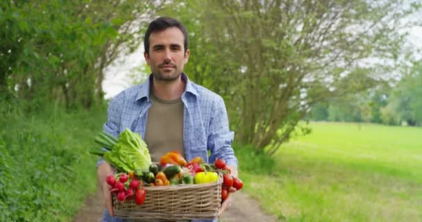 video van knappe Farmer man op het platteland te geven mand met oogst groenten  - Video