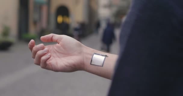 partial view of man, cropped video of man showing microchip on hand, blurred background with walking people - Footage, Video