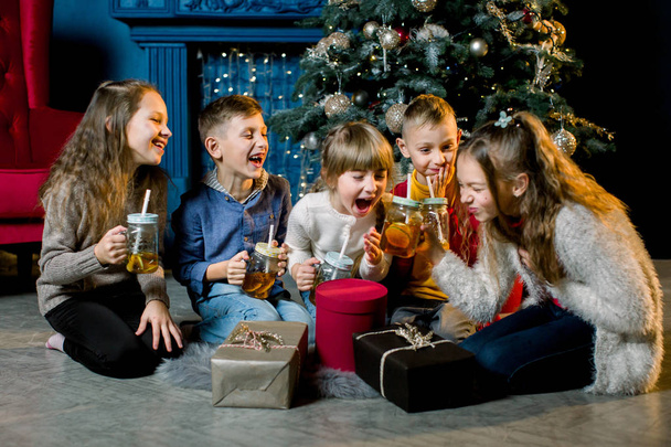 Merry Christmas and Happy Holidays. Young children drink lemonade and tell each other Christmas stories and laugh - Fotoğraf, Görsel