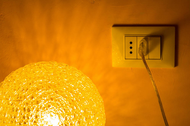 Netzstecker durch eine beleuchtete Tischlampe - Foto, Bild