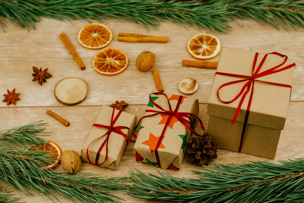 Christmas decorations. Pine branches, cinnamon sticks and dry oranges and gift boxes on a wooden surface. - Foto, Imagen