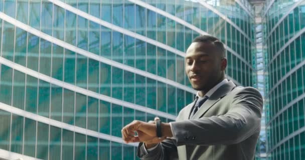 video van Afro-Amerikaanse zakenman aanraken met vinger hologram pictogram op polshorloge en bellen naar vriend  - Video