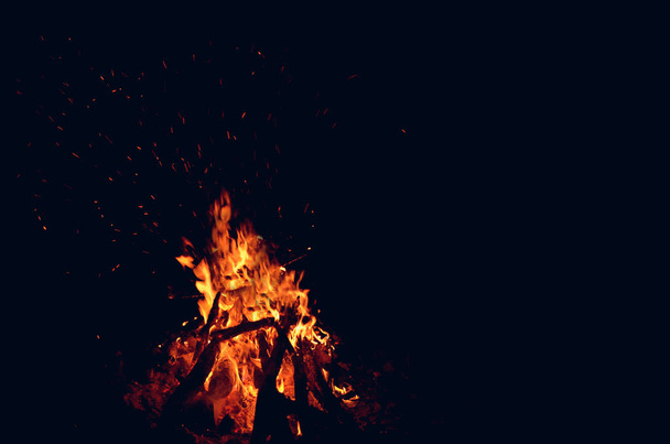 μεγάλη πυρκαγιά σκέδαση σπινθήρες στο σκοτάδι σε μαύρο φόντο - Φωτογραφία, εικόνα