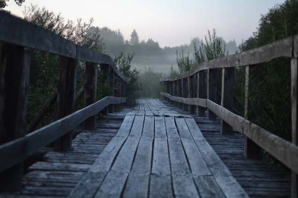 старый деревянный пешеходный мост в густом утреннем тумане - дорога вдалеке
 - Фото, изображение