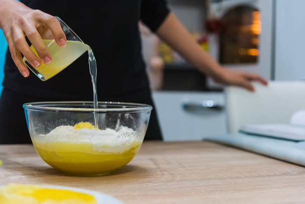 Femme versant du jus de citron dans une pâte à gâteau
 - Photo, image