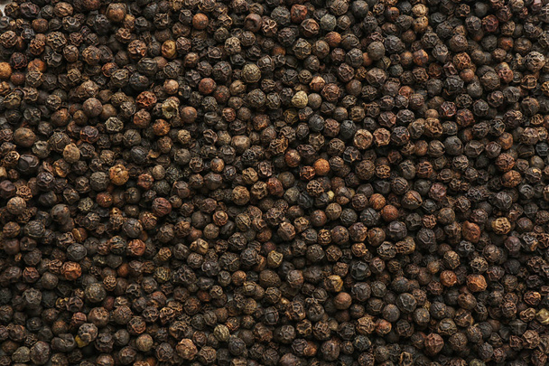 Black pepper corns as background. Natural spice - Foto, afbeelding