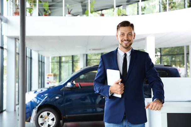 Salesman with tablet in modern car dealership - Фото, зображення