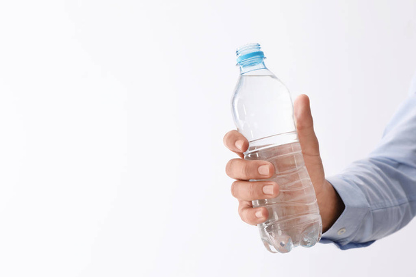 Man holding bottle of pure water on white background, closeup. Space for text - Zdjęcie, obraz