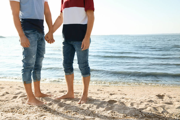 Gay couple standing barefoot on beach. Space for text - Foto, immagini