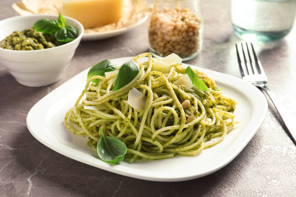 Plate with delicious basil pesto pasta on gray table - Фото, изображение