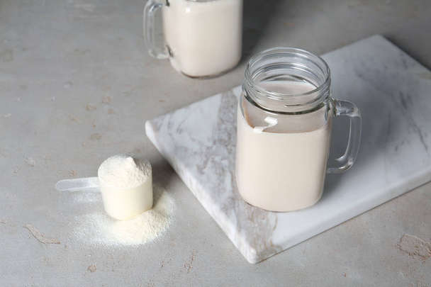 Mason jar with protein shake and scoop of powder on table - Foto, afbeelding