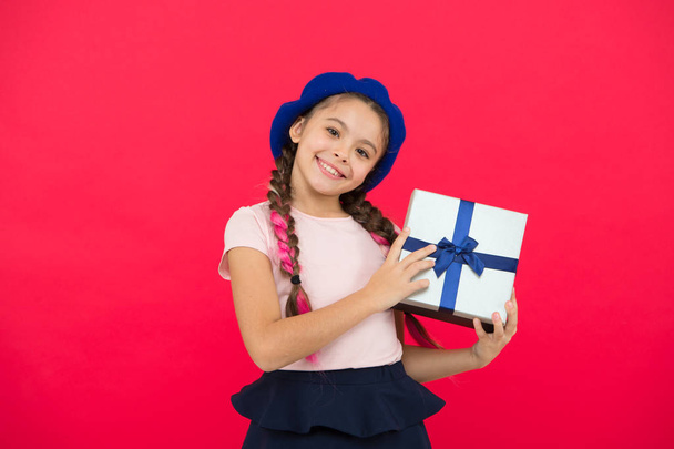 Kid little girl in beret hat hold gift box. Child excited about unpacking gift. Small cute girl received gift pack with ribbon bow. Guess what your child dream about. Best toys and christmas gifts - 写真・画像