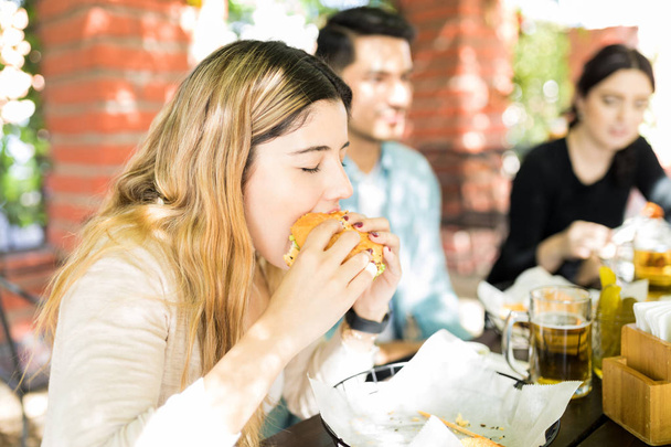Mulher bonita com os olhos fechados comer junk food insalubre durante a reunião
 - Foto, Imagem