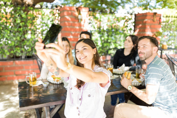 Souriant jeune femme prenant autoportrait avec des amis au restaurant de restauration rapide
 - Photo, image