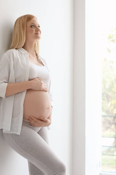 Portrait of beautiful pregnant woman near light wall - Фото, зображення