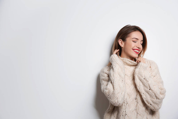 Beautiful young woman in warm sweater on white background. Space for text - Foto, afbeelding