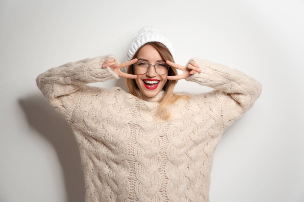 Beautiful young woman in warm sweater with hat on white background - Foto, Imagen