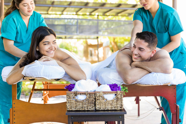 Usmívající se muž dívá na přítelkyni při příjmu masáž od masérky v luxusních lázních - Fotografie, Obrázek