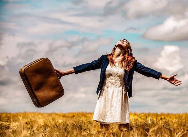 Vöröshajú lány a búzamező bőrönddel - Fotó, kép