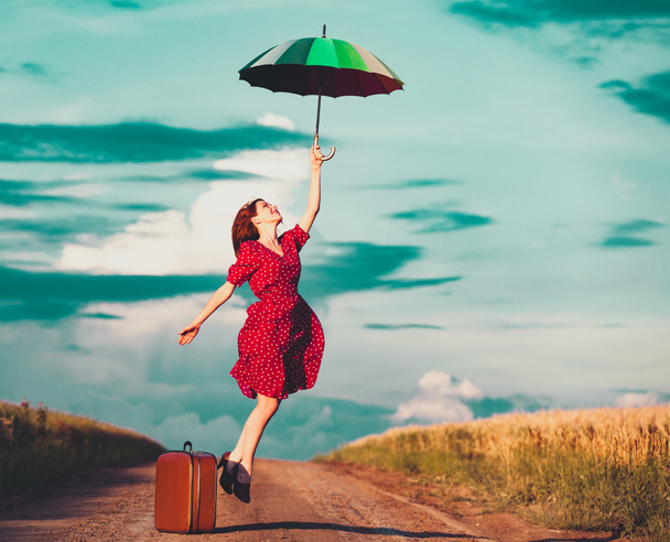 girl with umbrella and suitcase at countryside - Photo, Image