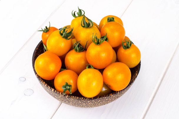 Golden yellow cherry tomatoes in wooden bowl. Studio Photo - Photo, Image