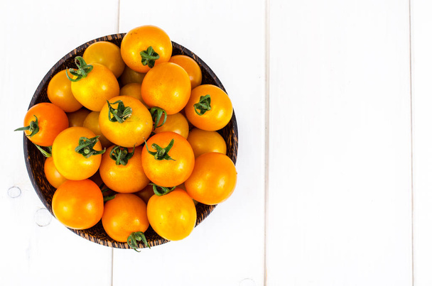 Golden yellow cherry tomatoes in wooden bowl. Studio Photo - Photo, Image