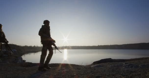 Żołnierzy maszerujących przez jezioro o zachodzie słońca - Materiał filmowy, wideo