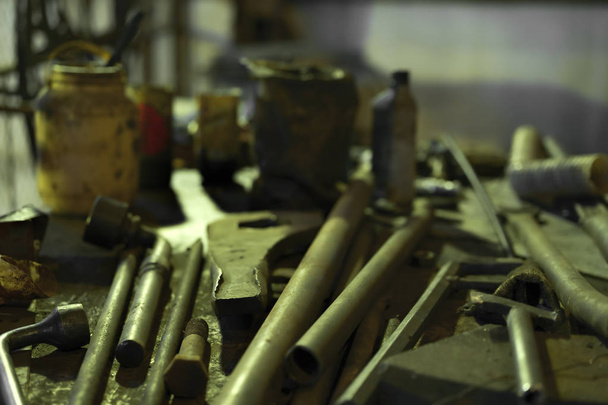 En la fábrica, una colección de herramientas viejas llave, martillo, tijeras para metal y llave de tubo están sobre la mesa
. - Foto, imagen