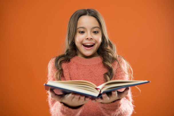 Child enjoy reading book. Book store concept. Wonderful free childrens books available to read. Childrens literature. Reading activities for kids. Girl hold book read story over orange background - Fotó, kép