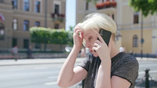Young Blonde Lady Speaking on the Phone in Town - Кадри, відео
