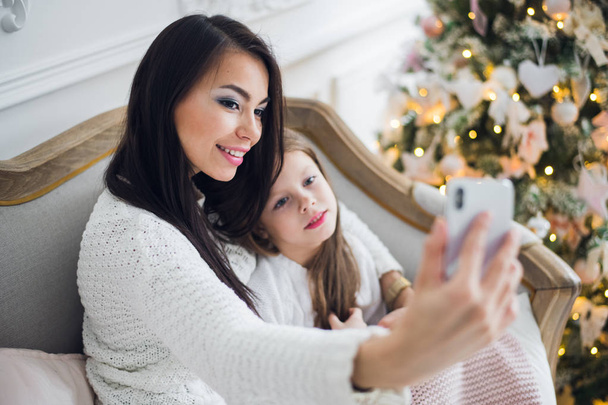 Well-groomed hand of a woman holding a phone taking a selfie with her daughter, little girl - Foto, Imagen