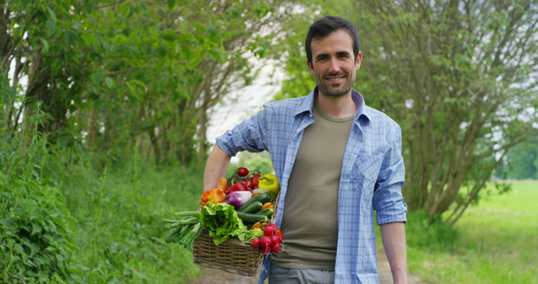 βίντεο του όμορφος αγρότης άνθρωπος στην ύπαιθρο κρατώντας καλάθι με λαχανικά συγκομιδής  - Πλάνα, βίντεο