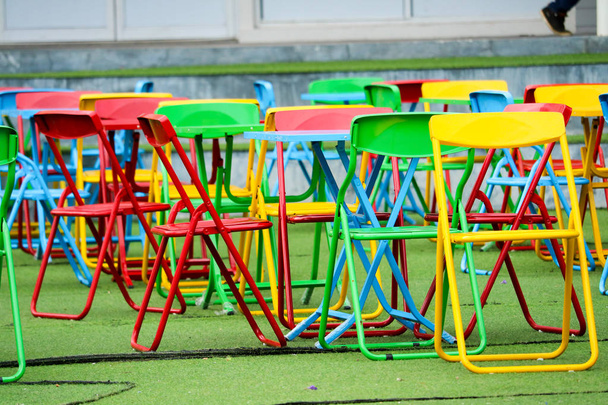 Monivärinen teräs tuoli asetettu vihreä muovi ruoho Julkinen leikkipaikka
 - Valokuva, kuva