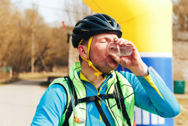 15 апреля 2018 года, Крево, Беларусь, Жуковая тропа: уставший велогонщик пьет воду после гонки
 - Фото, изображение