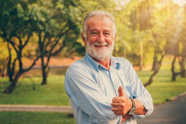 Πορτρέτο της ευτυχής ανώτερος άνθρωπος στέκεται στο πάρκο. Γέρων έννοια υγείας και συνταξιοδότησης. - Φωτογραφία, εικόνα