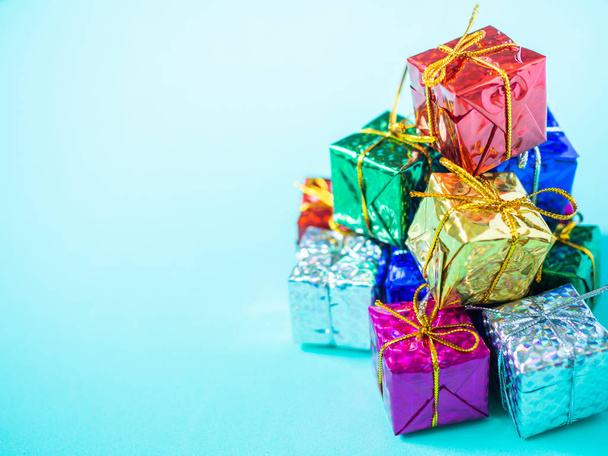 Pile de petites boîtes-cadeaux colorées sur fond bleu marine clair avec espace de copie. Vue du dessus de nombreux cadeaux enveloppés papier brillant coloré
. - Photo, image