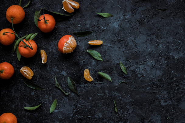 Vers mandarijnen met bladeren op gestructureerde donkere achtergrond met kopie ruimte. Bovenaanzicht. - Foto, afbeelding
