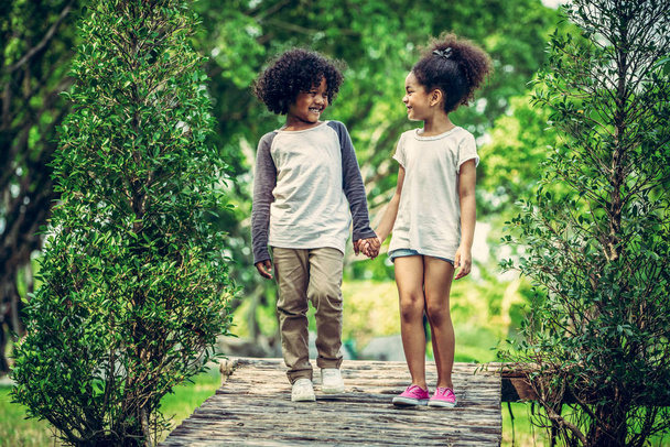 Gelukkig weinig jongen en meisje in het park. Twee Afro-Amerikaanse kinderen samen in de tuin. - Foto, afbeelding