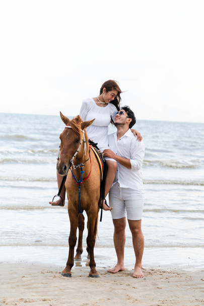 Młoda para idzie miesiąc miodowy konnej w letnie wakacje na plaży. - Zdjęcie, obraz