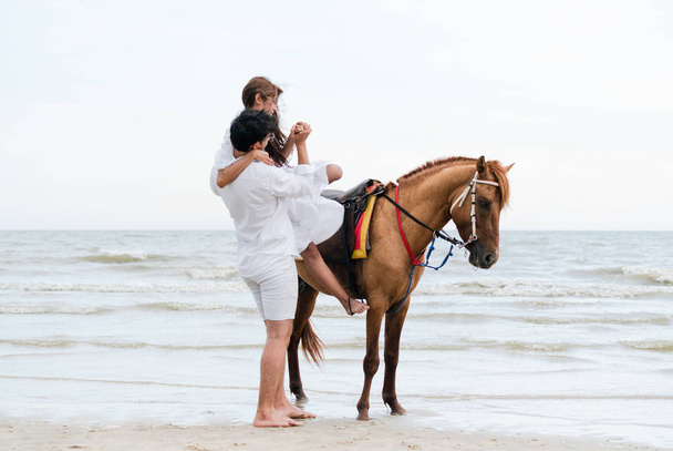 Giovane coppia va luna di miele a cavallo sulla spiaggia in vacanza estiva
. - Foto, immagini