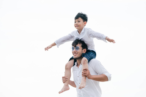 Onnellinen isä kantaa poikaansa kaulassa trooppisella hiekkarannalla kesällä
. - Valokuva, kuva