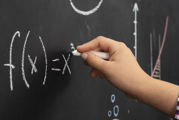 child's hand makes calculations on the blackboard - Foto, imagen