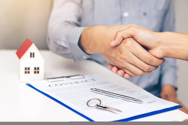 Zowel de kopers als de home verkoop-agenten werken betreffende ondertekening van nieuwe woningen en handen schudden. - Foto, afbeelding