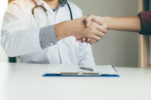 Doctor shaking hands with older patient in the office. - Foto, Bild