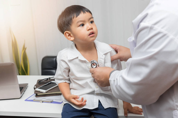 Pediatrician doctor examining a little asian boy by stethoscope - Fotografie, Obrázek