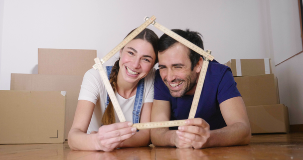 Portrait of a couple in love who have just bought a house and is moving. The bride and groom smile and hold the house-shaped meter in their hands. Concept of: future, family, mortgage and loan. - Footage, Video
