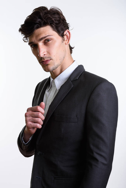 Studio shot of young handsome businessman holding suit - 写真・画像