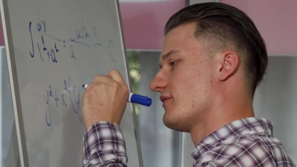 Knappe jongeman oplossen van wiskundige probleem op whiteboard - Video